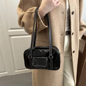 Retro black patent leather handbag with contrast stitching on a model in wool coat