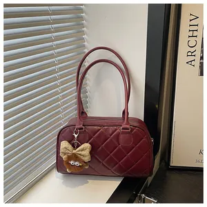 Close-up of wine red quilted handbag featuring a beige bow and plush teddy bear charm