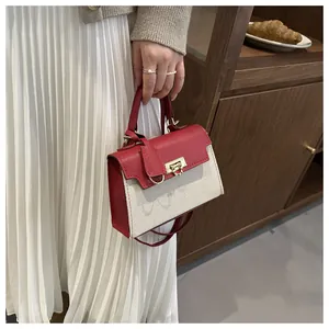 Detail of red and cream contrast handbag with gold hardware lock and woven canvas texture