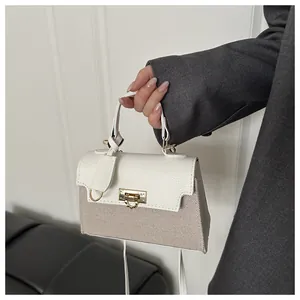 Detailed shot of the gold metal lock and contrast stitching on a chic square handbag