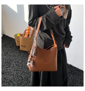 Close-up of brown litchi pattern leather bag with floral silk scarf and metal buckle detail