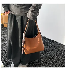 Detail of caramel leather hobo bag with pebble texture and polka dot silk scarf handle