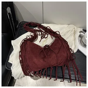 Détail du sac croissant bordeaux avec de longues franges bohèmes et texture en daim doux