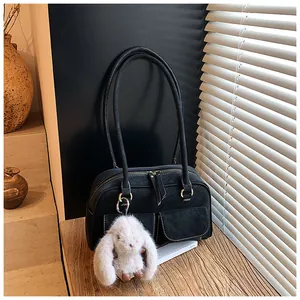 Close-up of black suede pillow bag with dual front pockets and white bunny charm