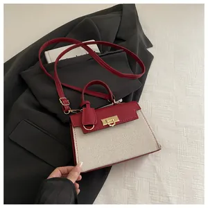 Close-up of golden rotating metal lock on red leather and cream canvas handbag