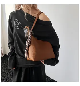 Brown litchi grain shoulder bag with elegant silk scarf detail shown on model