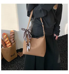 Close-up of brown litchi leather bag with silk scarf decoration and shoulder strap