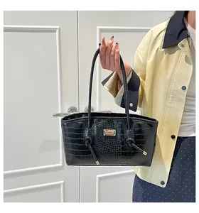 Macro detail of black crocodile texture bag with gold plaque and slim straps