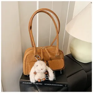 Detail of a brown suede pillow bag with dual front pockets and a cute rabbit charm