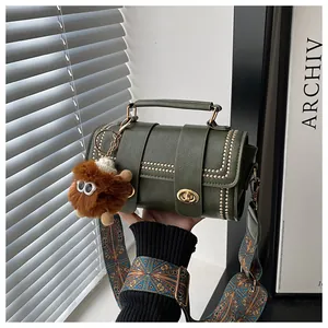 Detail of dark green cylindrical bag with gold metal studs and a colorful woven strap