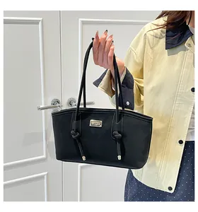 Close-up of quilted black tote bag with gold metal logo and knotted handle detail