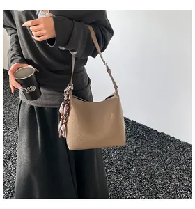 Brown litchi leather shoulder bag with polka dot scarf detail shown on a model