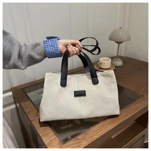 Détail d'un sac cabas en toile posé sur un bureau avec une tasse de café et une lampe