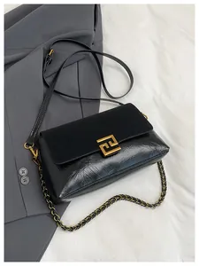 Detail of black glossy and matte leather flap bag with gold hardware and chain strap