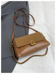 Macro detail of caramel brown textured bag with golden hardware and chain strap