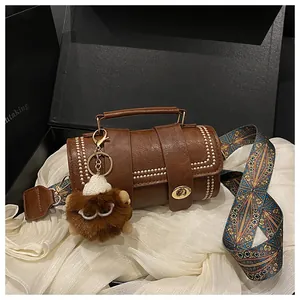 Detail of retro brown cylinder handbag with gold rivets and colorful ethnic shoulder strap