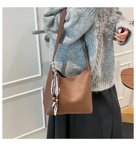 Detail of brown leather hobo bag with silk scarf ornament on grey knit sweater outfit