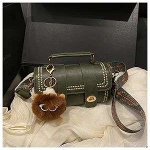 Detailed view of green cylindrical handbag with gold rivets and colorful patterned strap