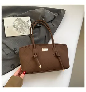 Detail of coffee brown quilted tote bag featuring knotted handles and gold metal branding