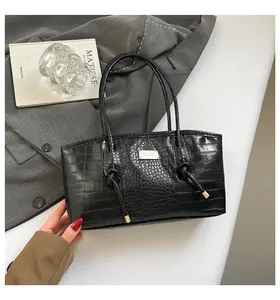 Detailed view of black crocodile pattern leather tote with gold logo and side knot