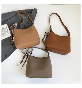 Detailed view of lychee-textured handbags in brown and taupe with silk scarf accents