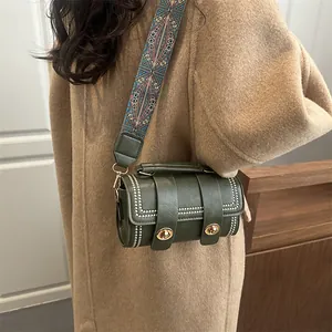 Dark green barrel crossbody bag with silver studs and colorful geometric wide strap