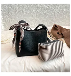 Close-up of black lychee grain leather bucket bag with silk scarf and striped pouch set