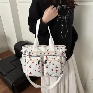 White canvas tote bag with red cherry patterns and multiple functional front zipper pockets