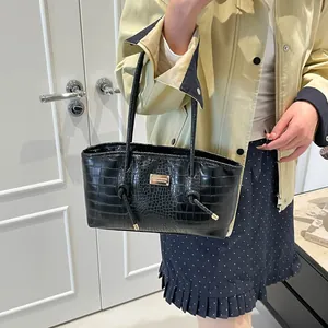 Elegant black crocodile pattern tote bag with metal logo, showcased on a model's arm