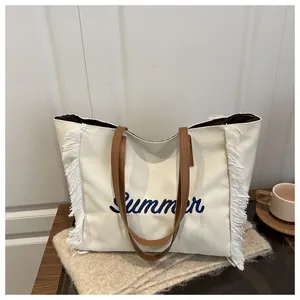 Détail du sac cabas en toile blanc cassé avec broderie Summer bleue et anses en cuir