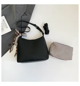 Detail of black lychee leather crossbody bag with silk scarf handle and small pouch