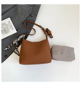 Close-up of brown textured leather hobo bag with printed silk scarf and striped inner pouch