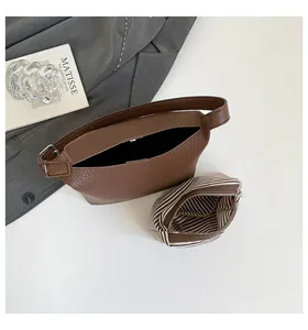 Detail of dark brown lychee grain leather tote with striped canvas inner pouch and magnetic buckle