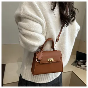 Brown faux leather crossbody bag with golden twist lock worn by a model in casual outfit