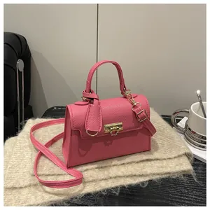 Detailed close-up of pink litchi grain leather handbag with gold metal lock on a scarf