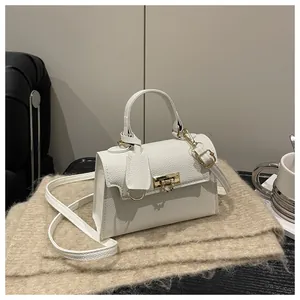 Detail shot of white lychee grain leather mini bag with gold hardware on soft knit fabric