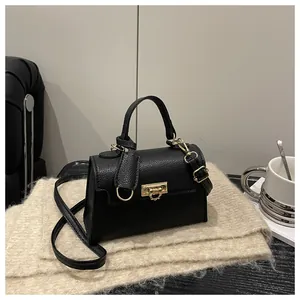 Detail of black litchi texture leather crossbody bag with elegant gold square lock