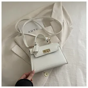 Detail of white lychee leather texture and golden metal twist lock on top-handle bag