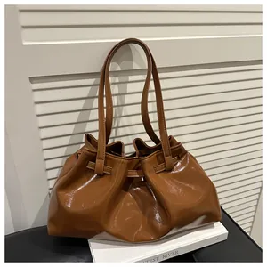 Detailansicht der braunen plissierten Cloud-Tasche mit Glanzeffekt auf Dekobüchern