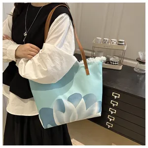 Detalle del bolso tote con degradado azul, bordes deshilachados y asa de cuero