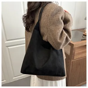 Close-up of black suede tote bag shown on model in a stylish vintage casual outfit