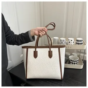 Détail de la texture tressée blanche et des finitions en cuir marron du sac cabas