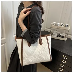 Détail du sac cabas blanc tissé avec bordure marron et fine bandoulière élégante