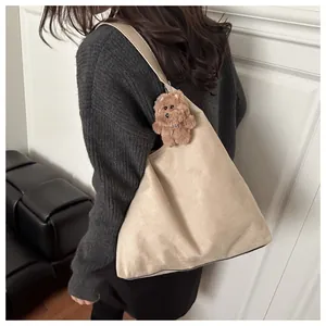 Detail of beige suede tote bag with brown plush bear charm and knitted sweater outfit