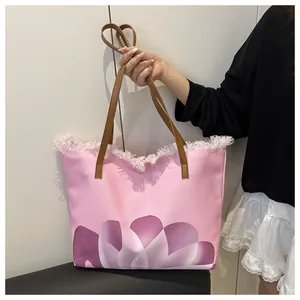 Detalle de bolso tote rosa con estampado floral, flecos y correas de cuero marrón