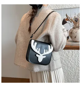 Détail du sac bandoulière avec broderie de renne blanc sur similicuir noir élégant