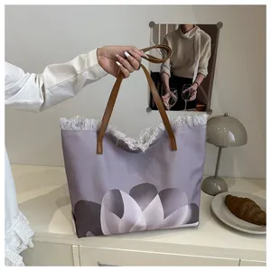 Detalle del bolso tote de lona floral con flecos blancos y asas de cuero marrón café