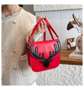 Gros plan du sac bandoulière rouge avec tête de cerf 3D tenu par un mannequin en intérieur