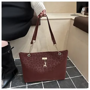 Dettaglio borsa shopper bordeaux leopardata con ciondolo cervo dorato e catena