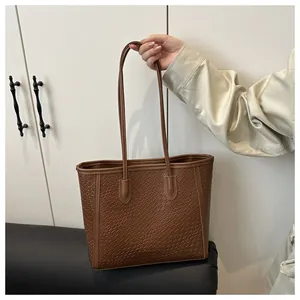 Détail de la texture tressée marron foncé et des fines anses d'un grand sac cabas